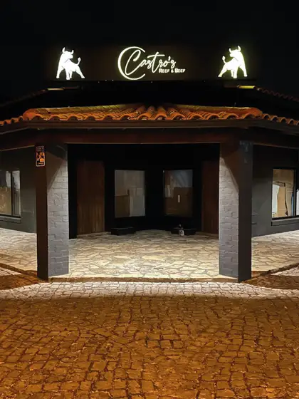 A frente do restaurante à noite, com o letreiro em néon.