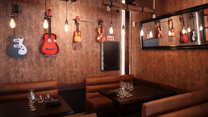 Bancos corridos em pele sob guitarras penduradas na parede.
