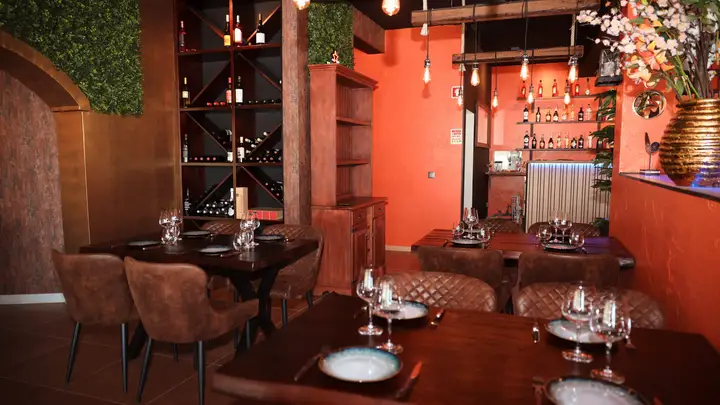 A sala de jantar, paredes cor de barro e garrafeiras à vista.