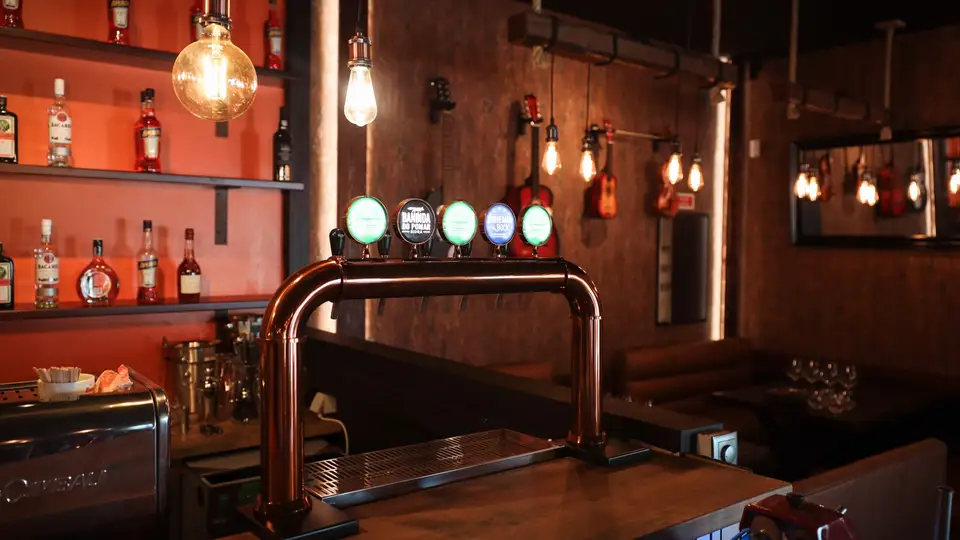 O balcão do restaurante, com a coluna de cerveja em cobre sob uma lâmpada de filamento.