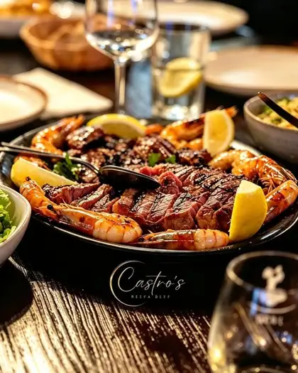 Travessa de carne grelhada com gambas, limão e legumes.